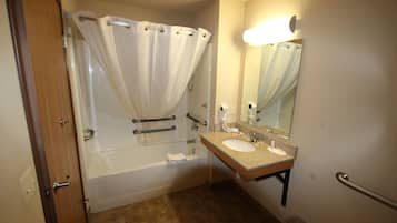 Un baño con bañera, lavamanos, espejo y cortina de ducha.