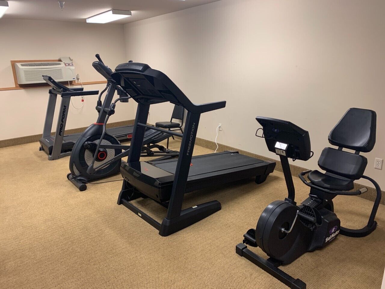 A fitness room with treadmills, a stationary bike, and a rowing machine.
