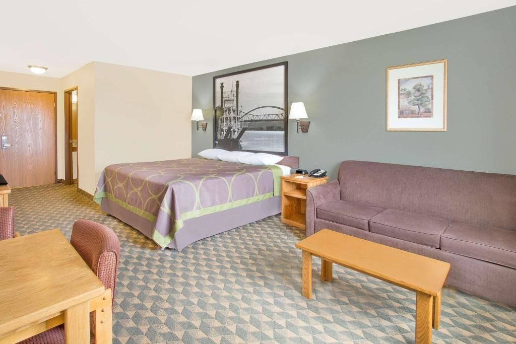 A hotel room with a bed, a sofa, a table, and a desk.