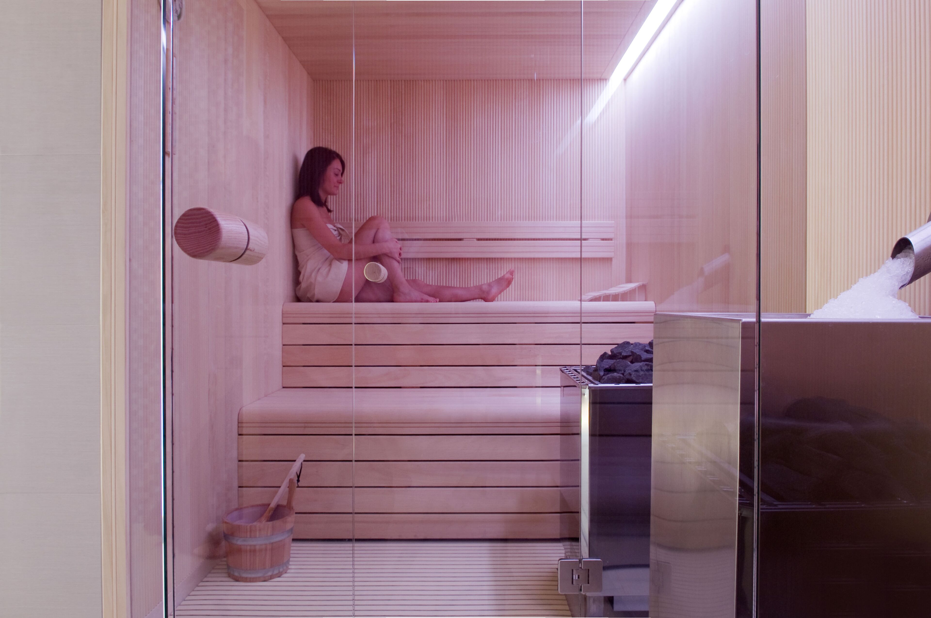 Un sauna avec des bancs en bois et une porte en verre.