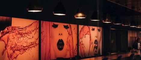 A bar area with a long counter, multiple hanging pendant lights, and bar stools.