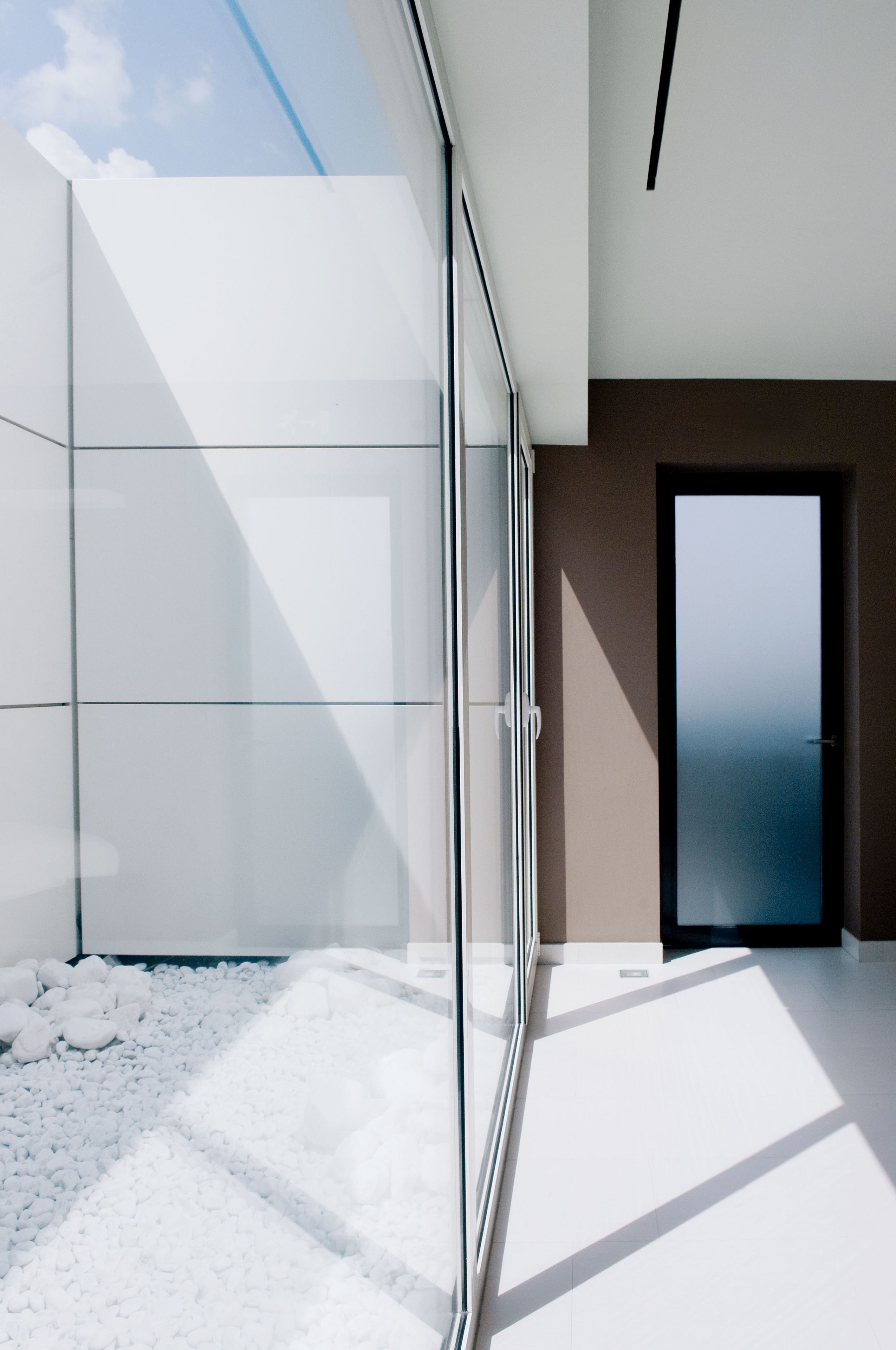Ein modernes Interieur mit einer Glastrennwand, einer Tür und einem Fliesenboden.