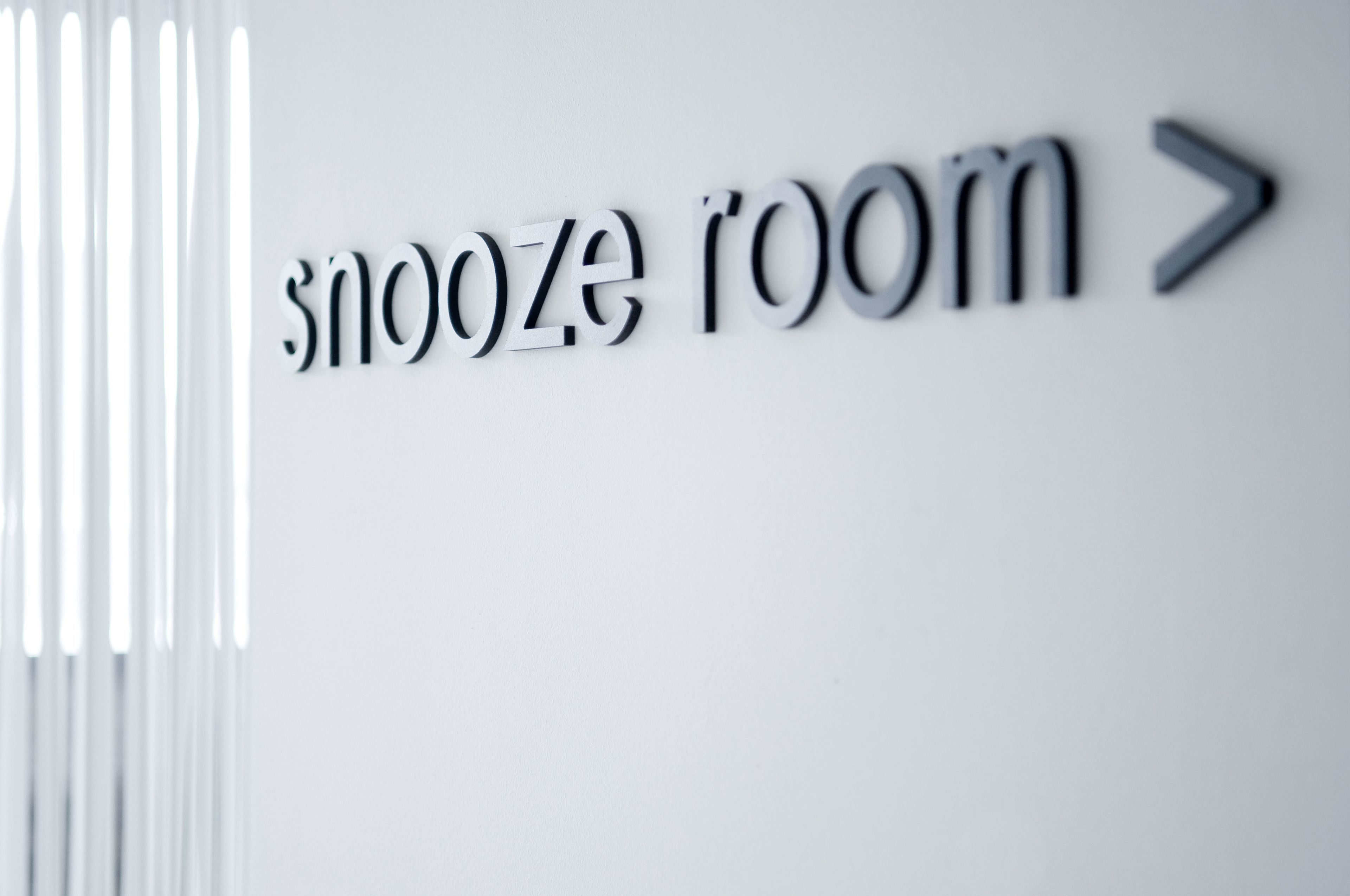 Una señal con el texto 'snooze room' y una flecha apuntando a la derecha.