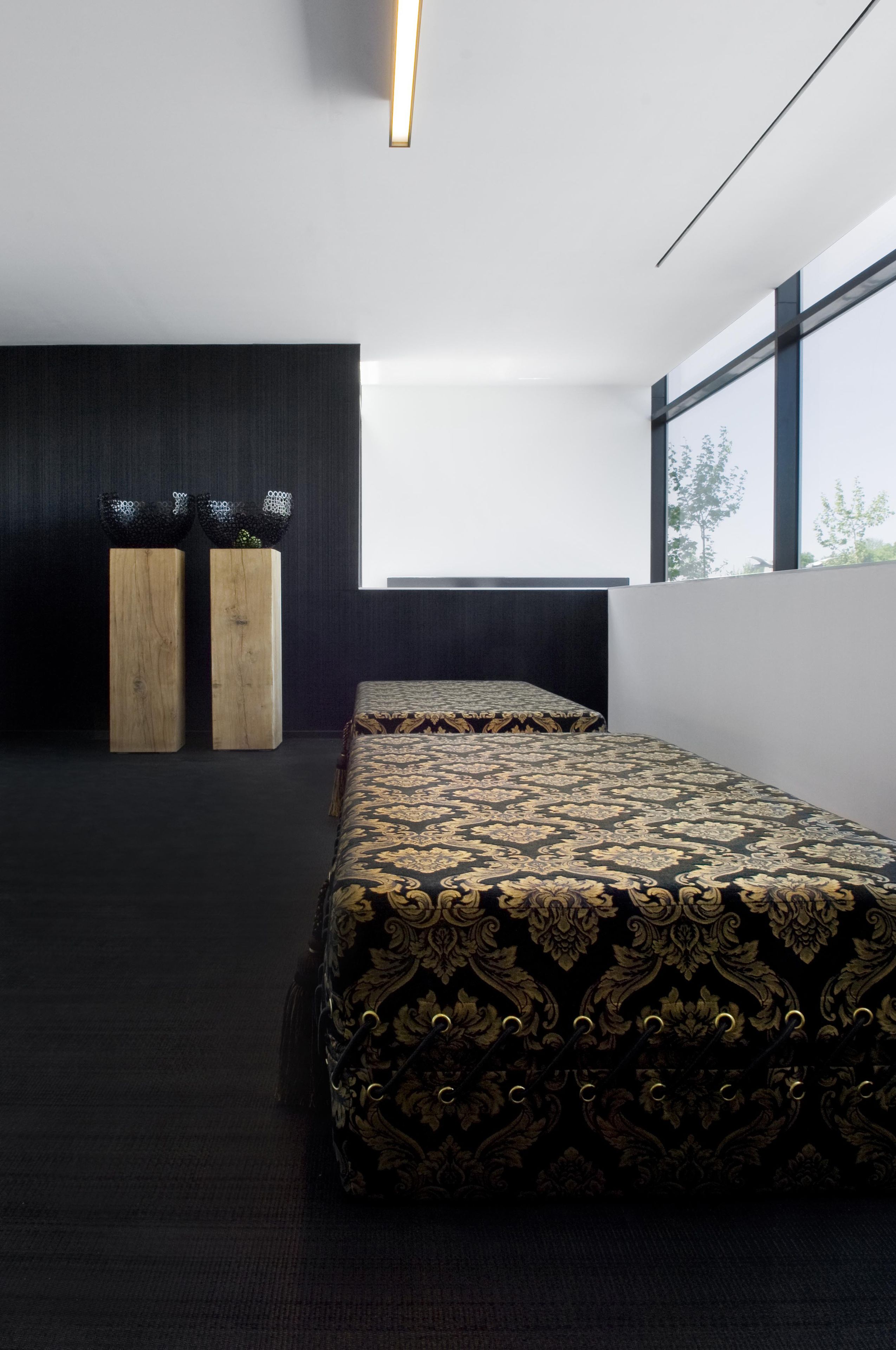 Une chambre moderne avec deux lits, des tables de chevet en bois et une grande fenêtre laissant entrer la lumière naturelle.