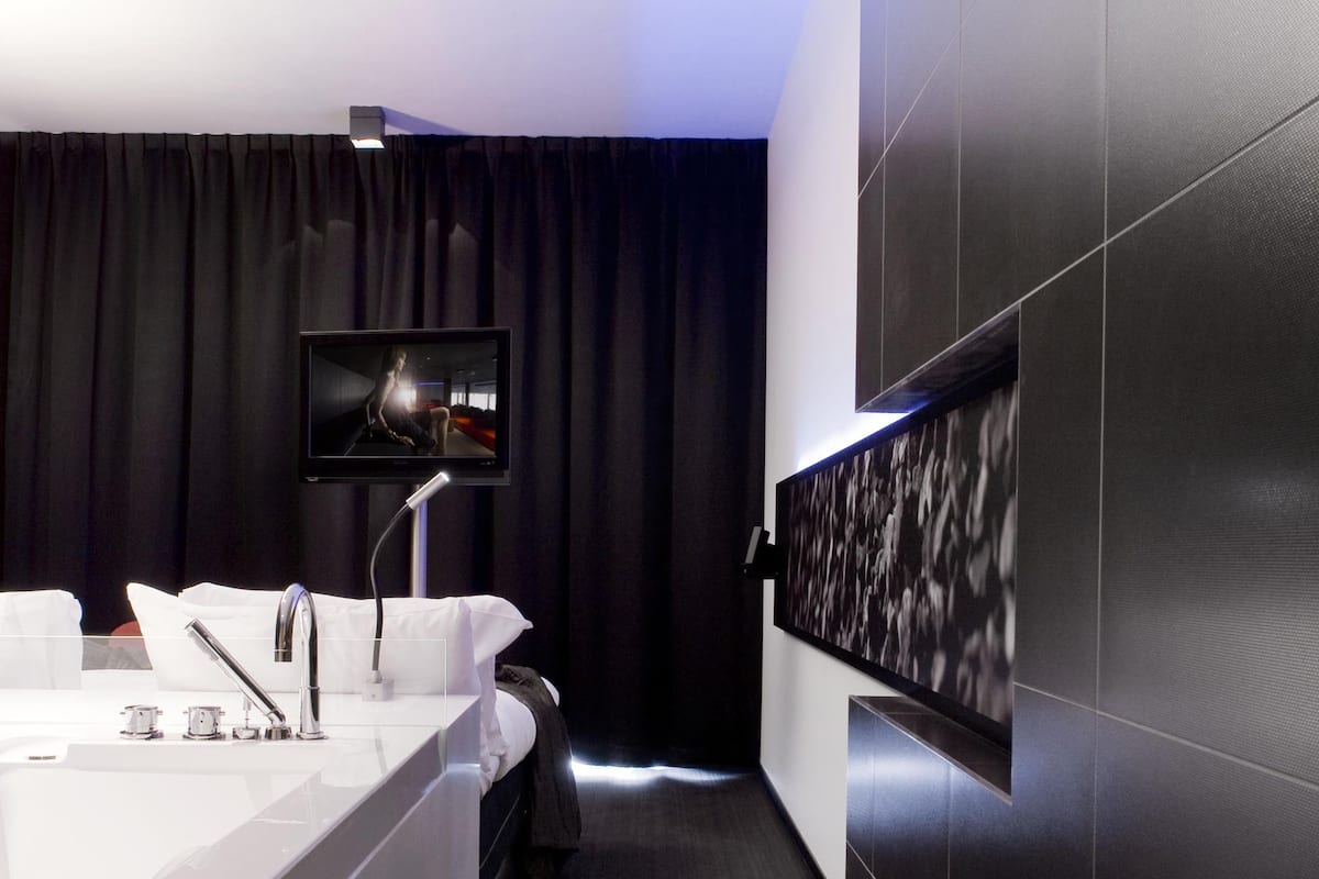 A modern bathroom with a large mirror, a sink, and a television mounted on the wall.
