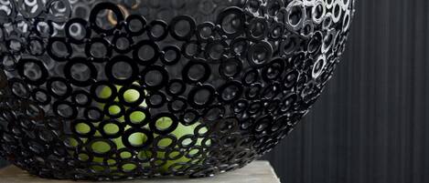 Un bol métallique orné d’un motif circulaire, posé sur une surface en bois, le tout sur un fond sombre.