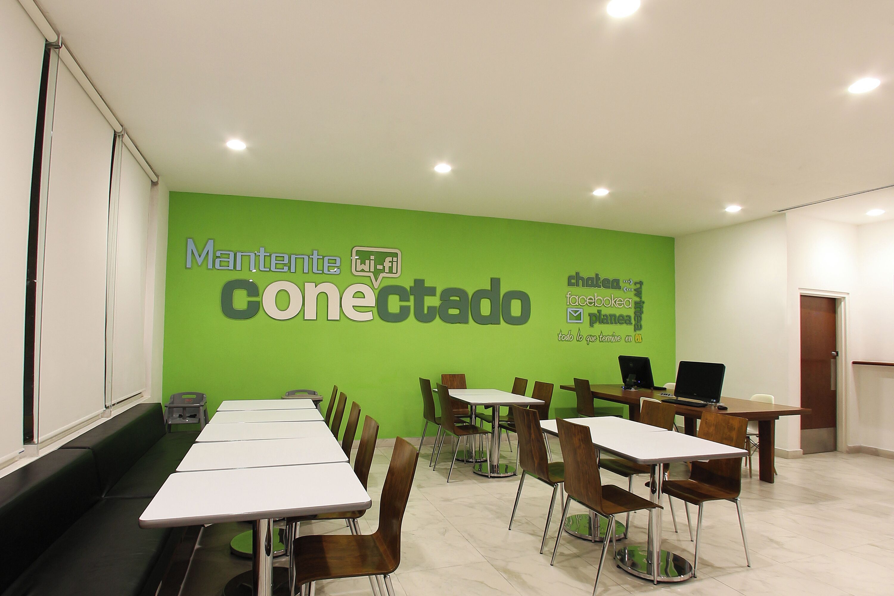 A conference room with a green wall, white tables, and chairs.