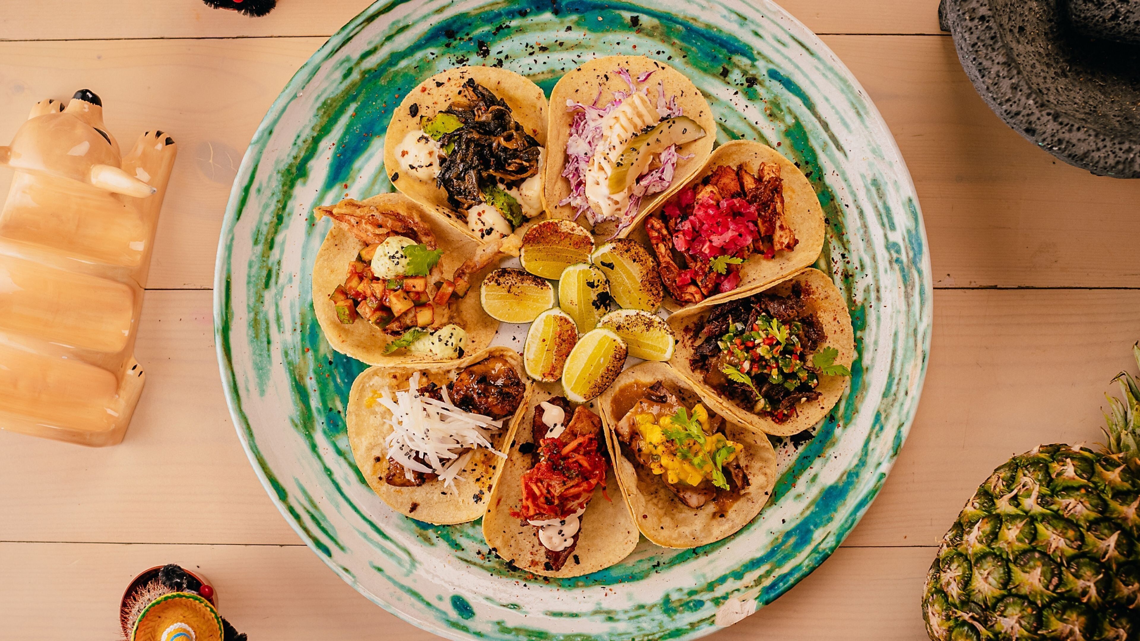 A plate of tacos with various toppings and a pineapple on the side.