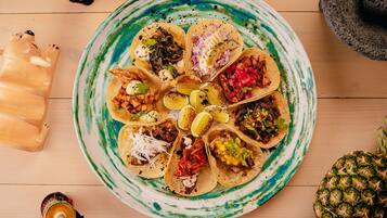 Un plato de tacos con diversos ingredientes y una piña al lado.
