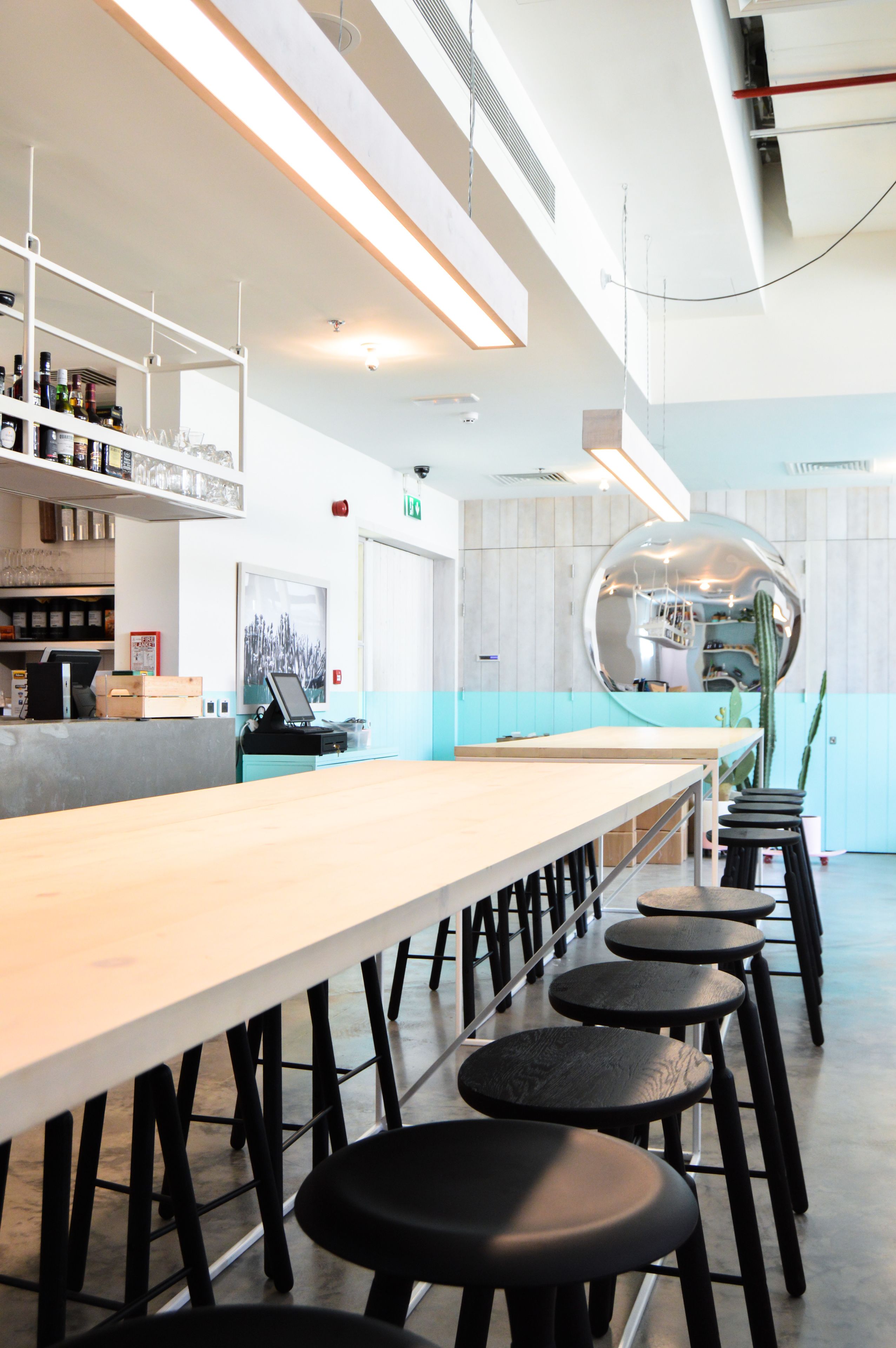 A modern bar area with a long counter, stools, and a unique spherical mirror decoration.