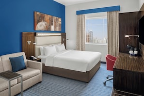 A hotel room with a large bed, a desk, a chair, a TV, and a city view. - Holiday Inn Express Dubai Safa Park by IHG (Dubai)