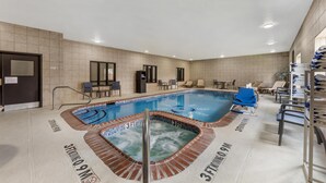 Una piscina con hidromasaje, sillas de descanso y un muro de azulejos.