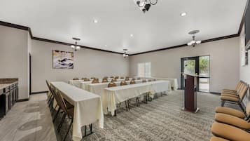 A conference room with long tables, chairs, a podium, and a chandelier.