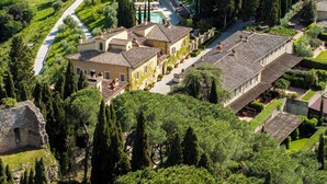 Vista aérea de una villa con piscina, jardines en terrazas y un camino de piedra.