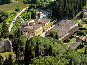Vista aérea de una villa con piscina, jardines en terrazas y un camino de piedra.