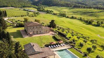 A large estate with a swimming pool, a tennis court, and a vineyard.