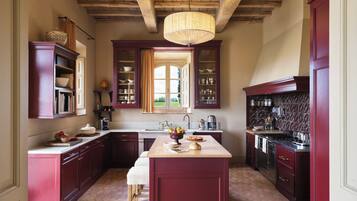 A kitchen with dark wooden cabinets, a central island, and a hanging light fixture.