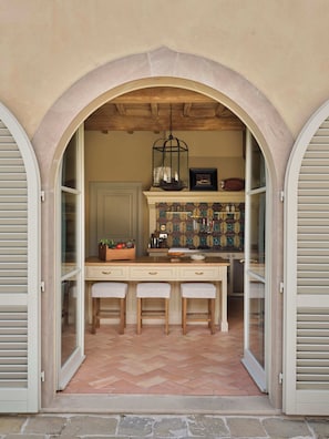 Un arco abierto que da a una cocina con techo de madera, un farol colgante y salpicadero de azulejos.