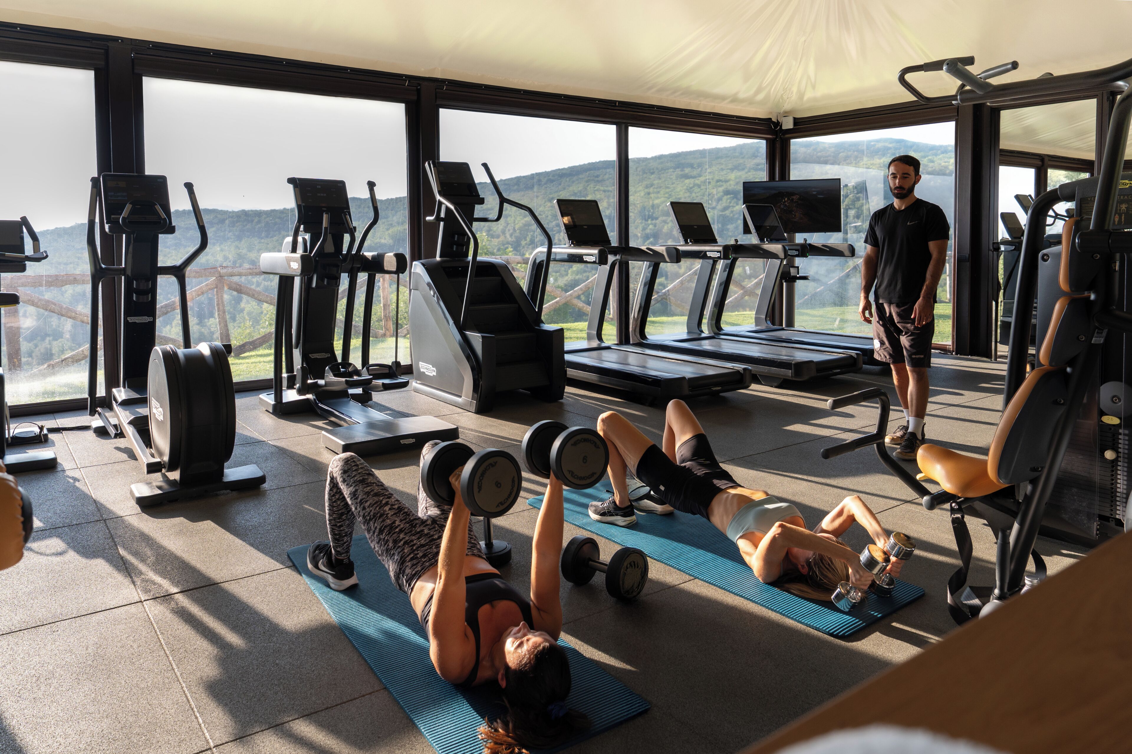 A gym with exercise equipment, a treadmill, and a person standing.