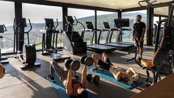 A gym with exercise equipment, a treadmill, and a person standing.