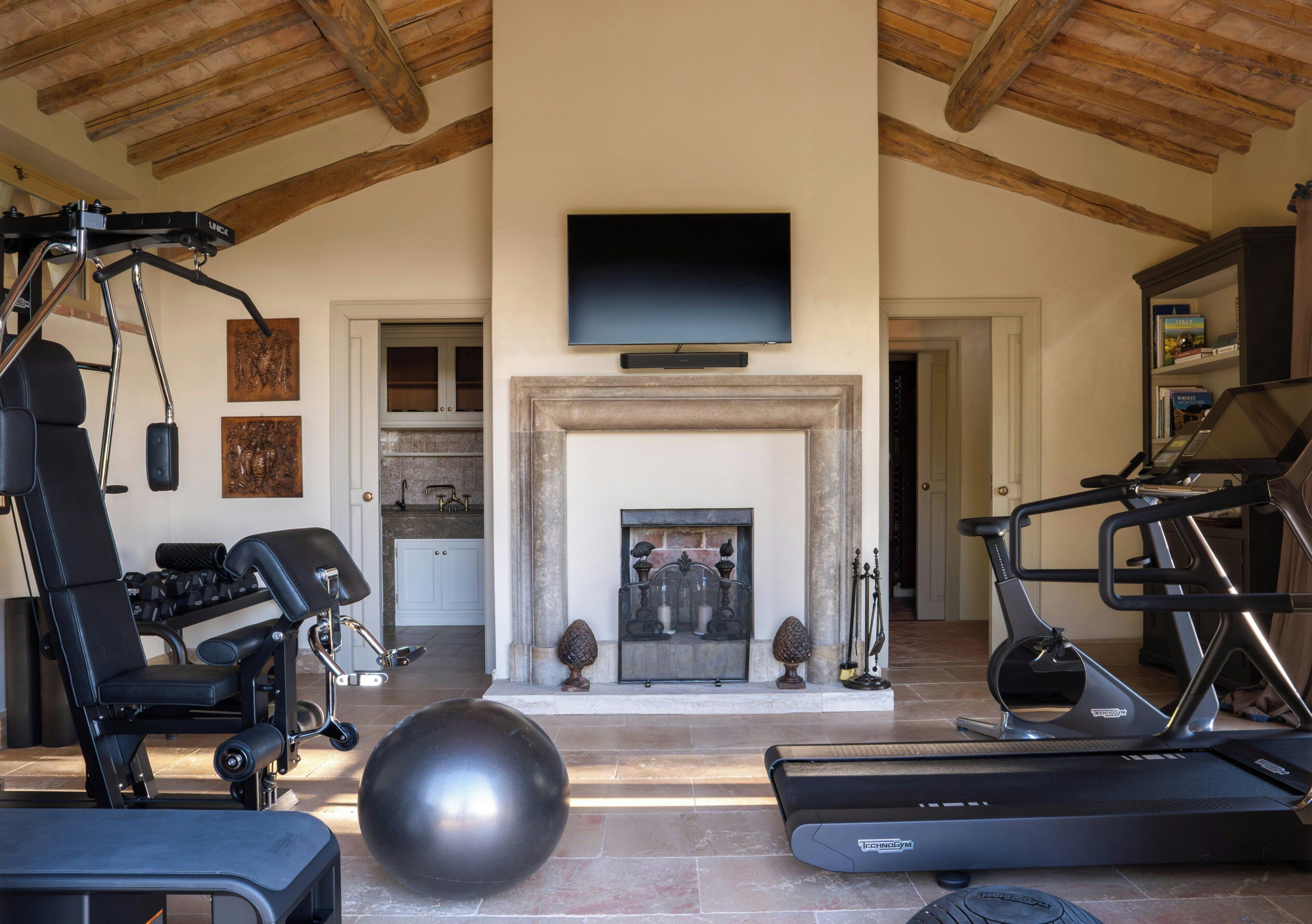 A home gym with exercise equipment, a television, and a fireplace.