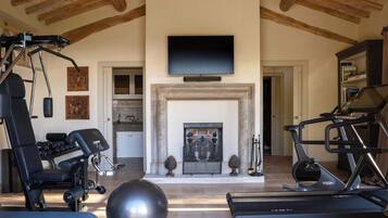 A home gym with exercise equipment, a television, and a fireplace.