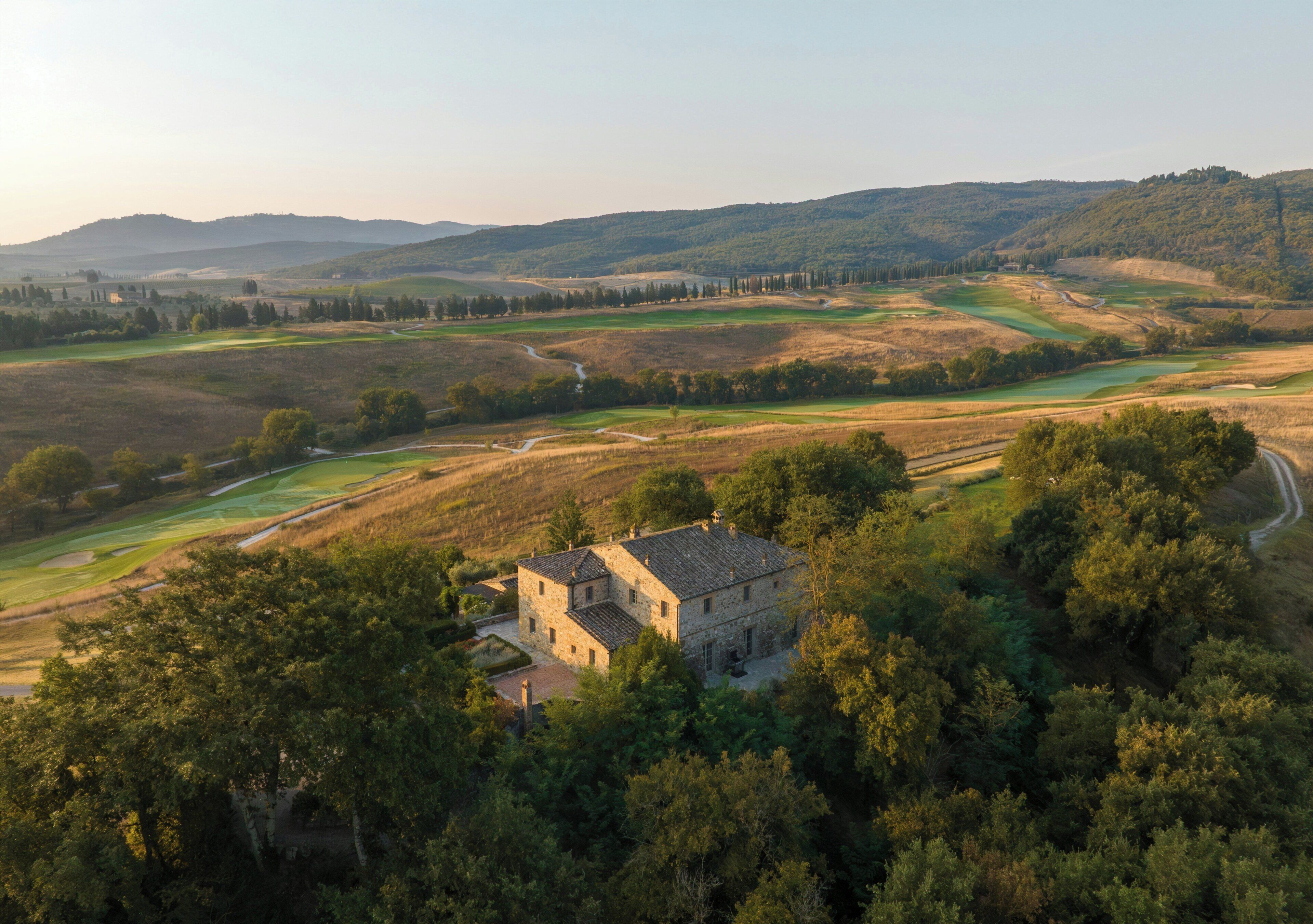 Un edificio in pietra circondato da alberi rigogliosi e da un campo da golf.