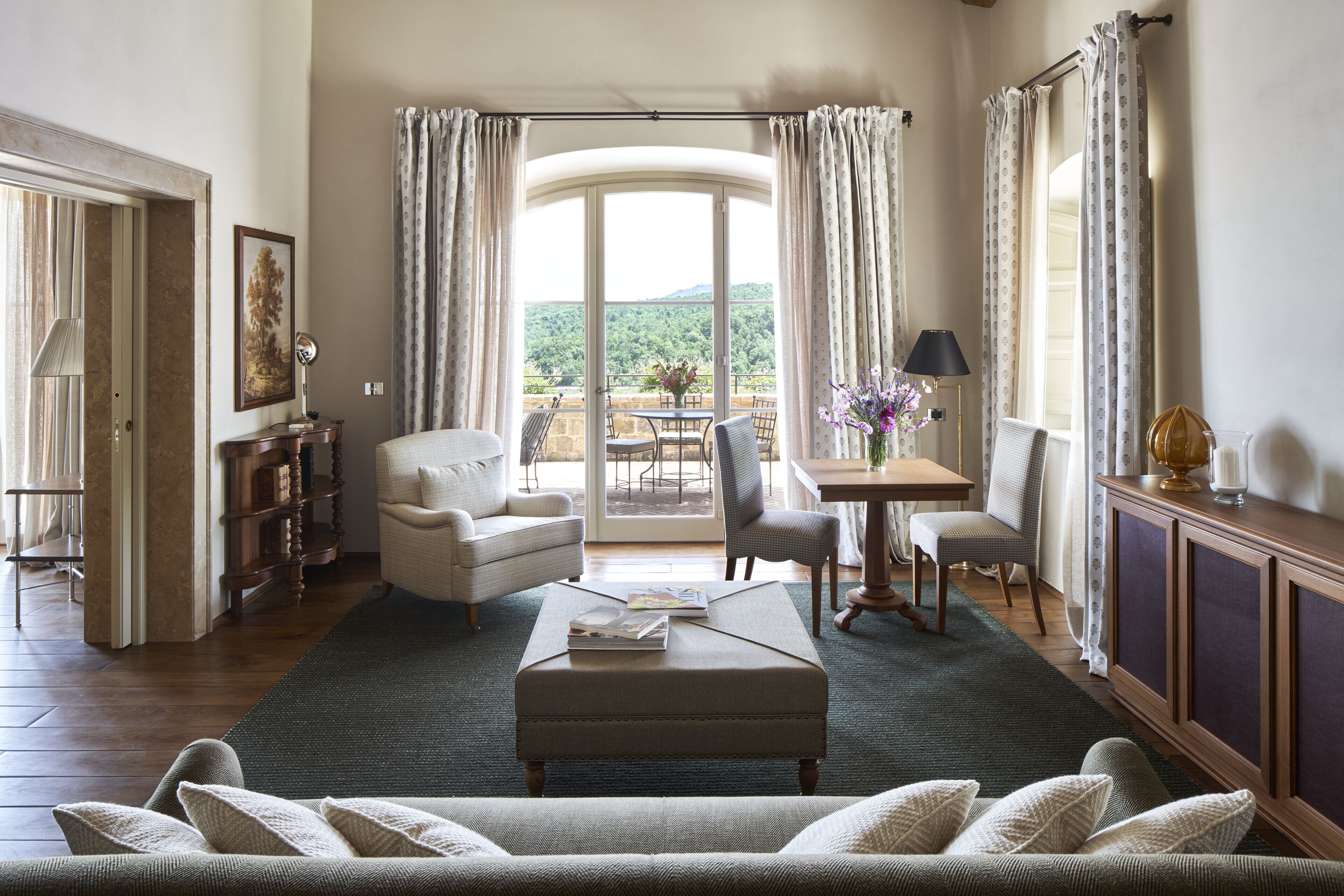 A spacious living room with a sofa, chairs, a coffee table, and a view through a glass door to an outdoor patio.