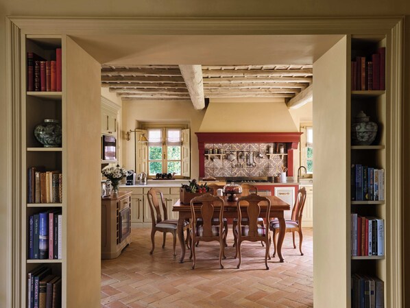 Un comedor con una mesa y sillas de madera, rodeado de estanterías llenas de libros.