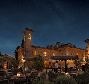 A historic building with a bell tower, outdoor seating, and a starry night sky. - Castiglion del Bosco, A Rosewood Hotel (Montalcino)