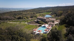 Una villa con piscina, rodeada de vegetación exuberante y vistas a colinas distantes.