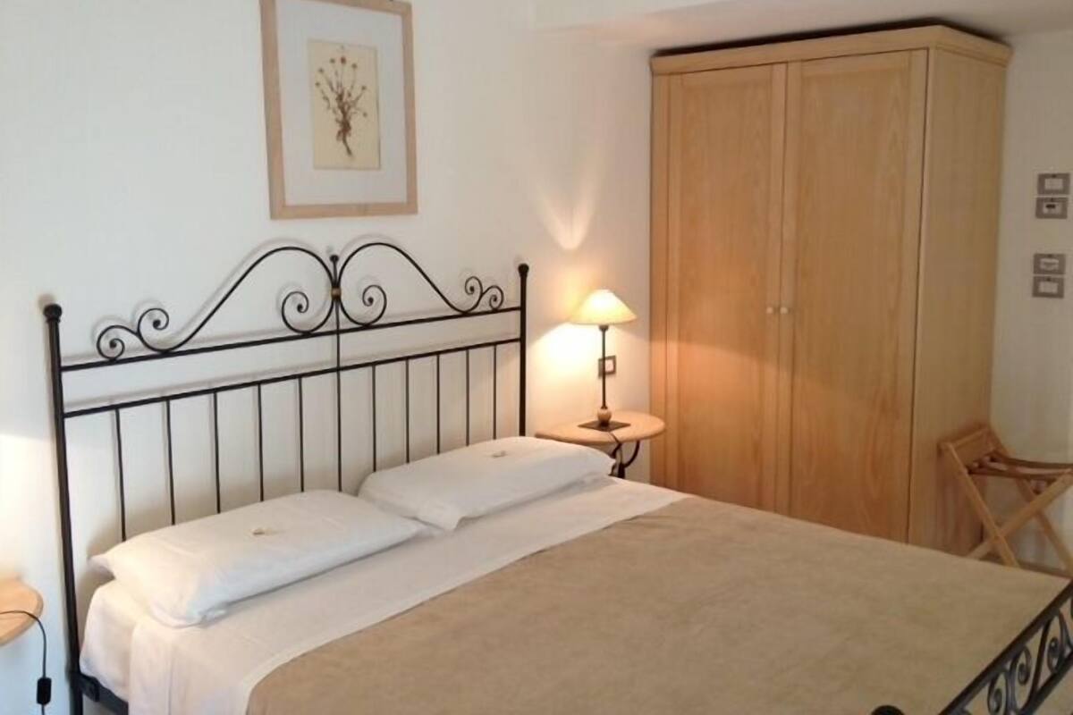 A bedroom with a bed, a bedside lamp, a wardrobe, and a framed picture on the wall.