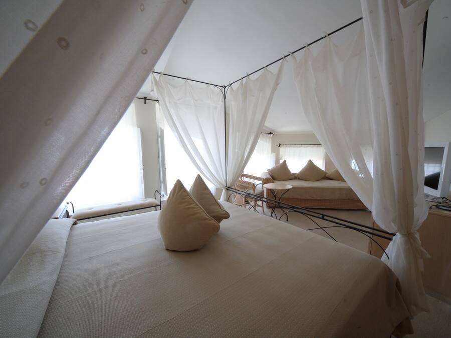 Un dormitorio con una cama grande, una cama más pequeña y un escritorio con una computadora.