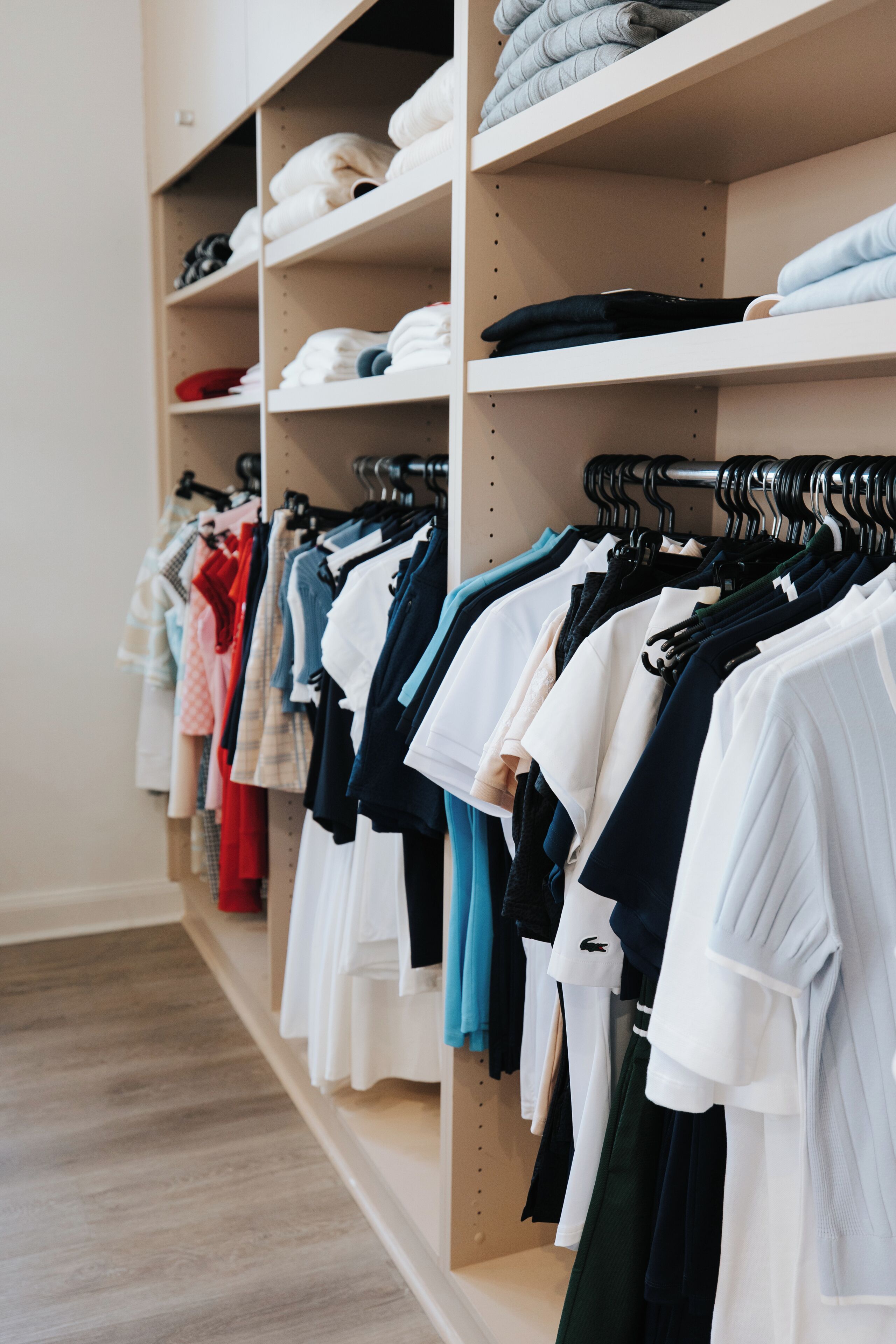 Un magasin de vêtements où les étagères et les portants sont bien rangés et présentent une variété de vêtements.