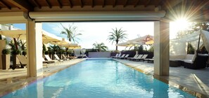 A swimming pool with sunshades and lounge chairs, surrounded by palm trees and a clear sky. - Hôtel Royal Mougins (Mougins)