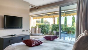 Een moderne hotelkamer met een groot bed, een flatscreen-tv, een balkon met een tafel en stoelen, en uitzicht op de omgeving.