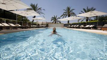 Una piscina al aire libre de temporada, sombrillas