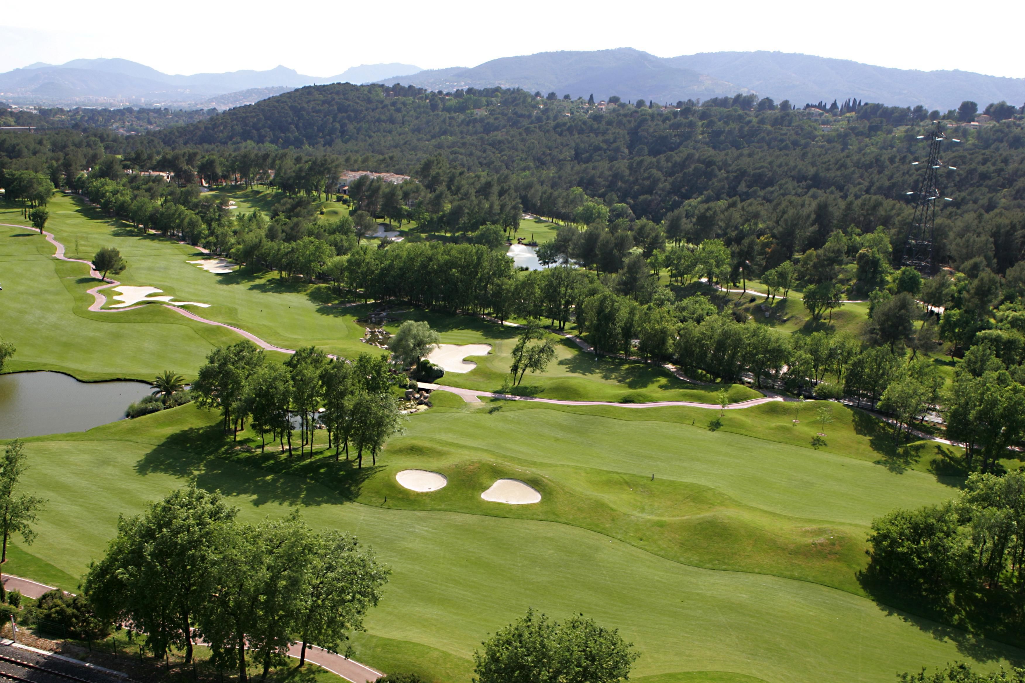 A golf course with multiple bunkers, water hazards, and a pond.