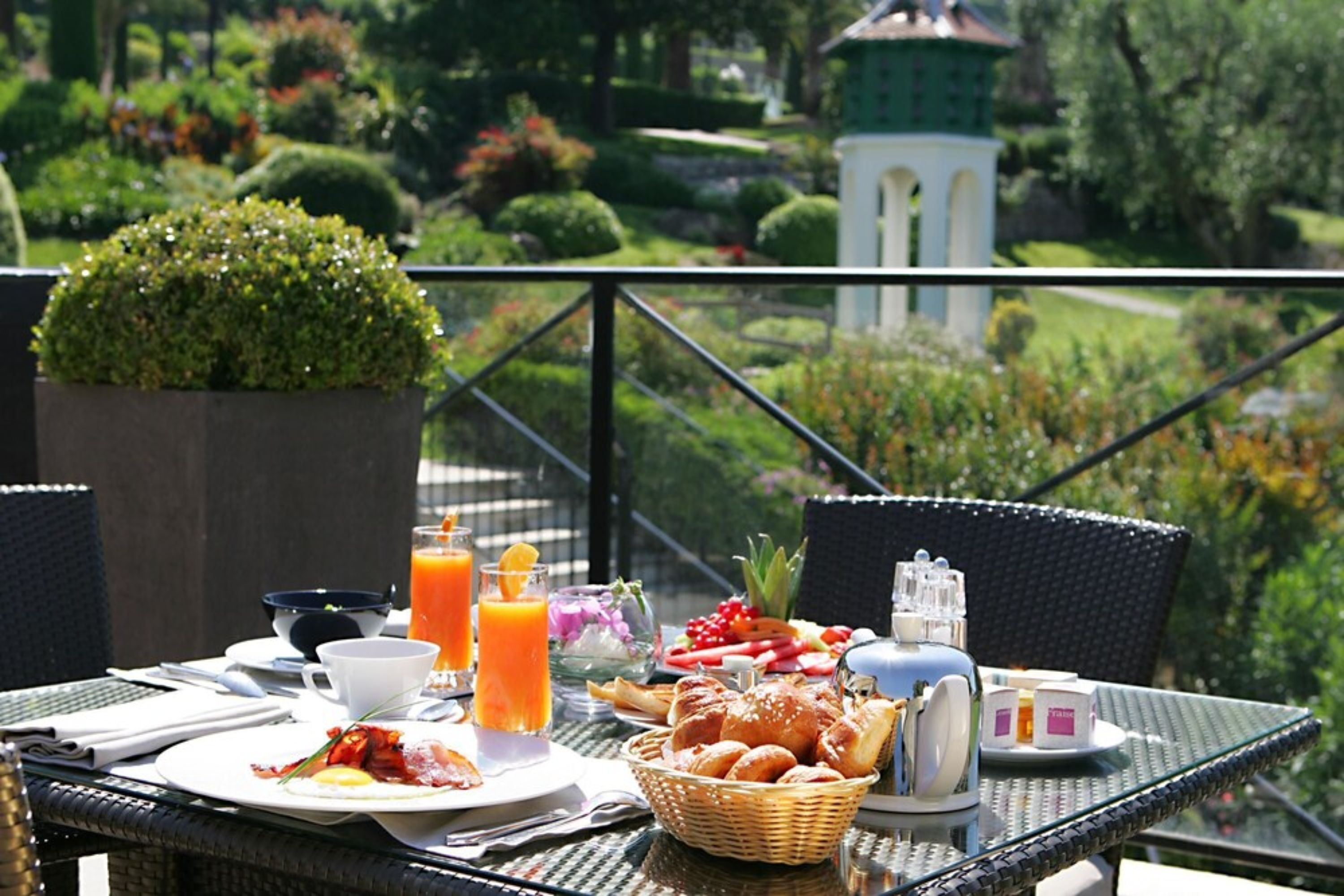 A breakfast table set outdoors with a view of a garden and a gazebo.
