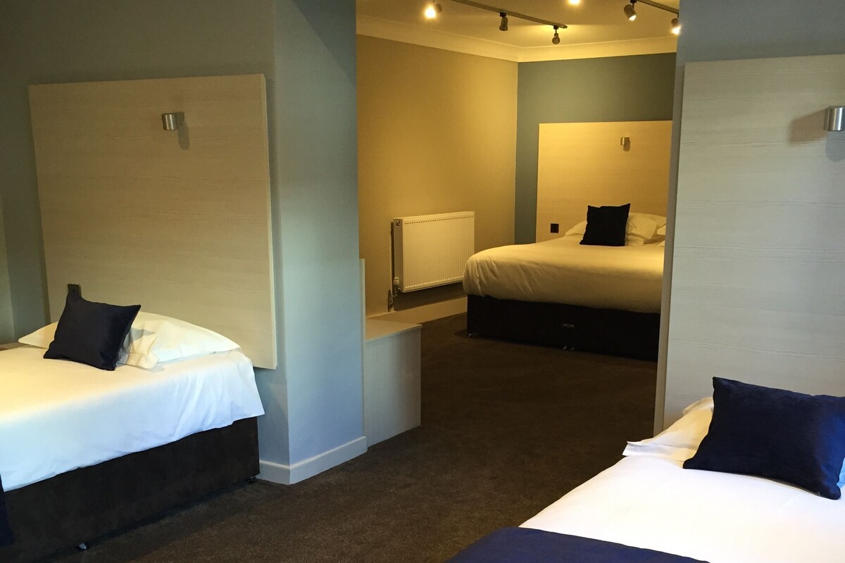 A hotel room with two beds, a radiator, and a mirror.