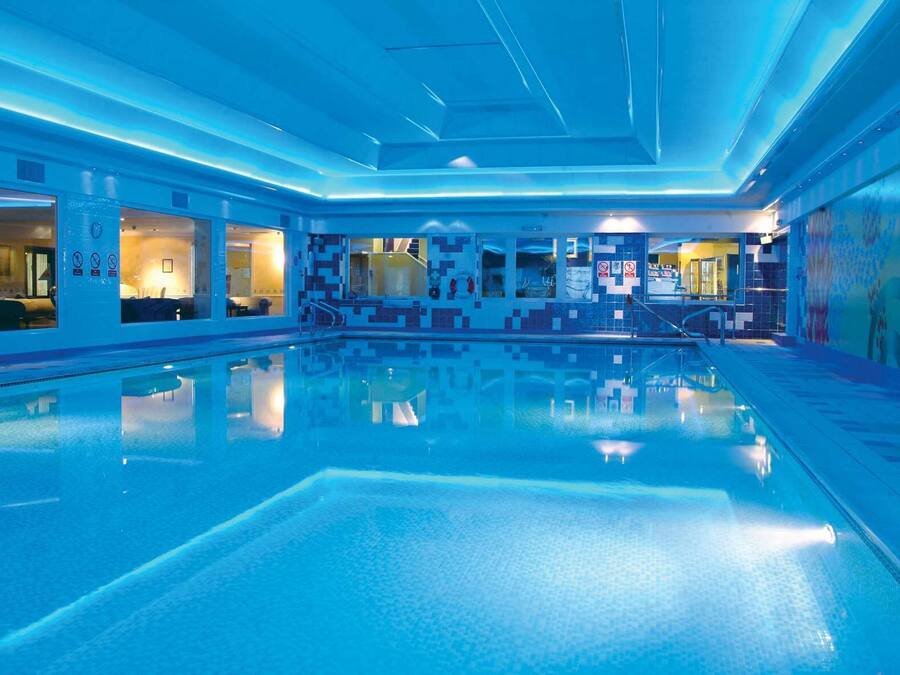 Een binnenzwembad, ligstoelen bij het zwembad