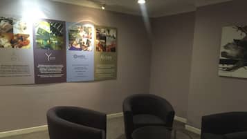 Una sala de conferencias con sillas tapizadas oscuras, una mesa de vidrio y una pared con carteles informativos.