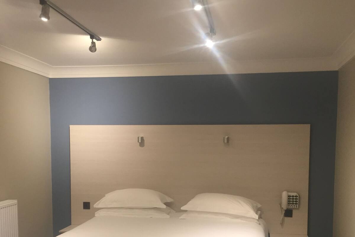 A hotel room with a large bed, a bedside telephone, and a radiator.