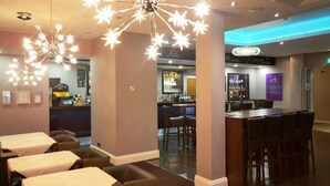 A hotel lobby with a bar area, seating arrangements, and a decorative ceiling light. - Dalmeny Resort Hotel (Lytham St. Anne's)