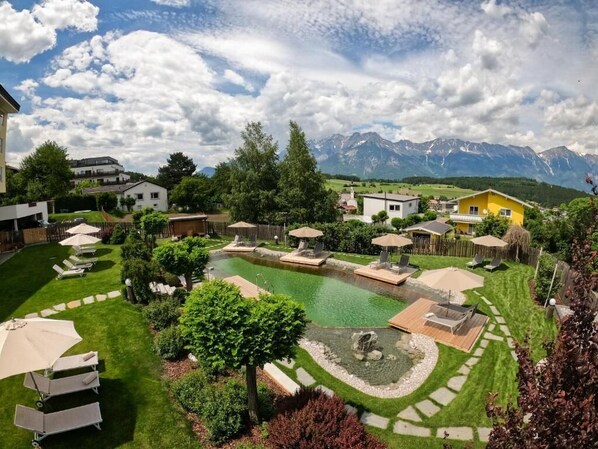 A residential area with a swimming pool, lounge chairs, and a mountain view.