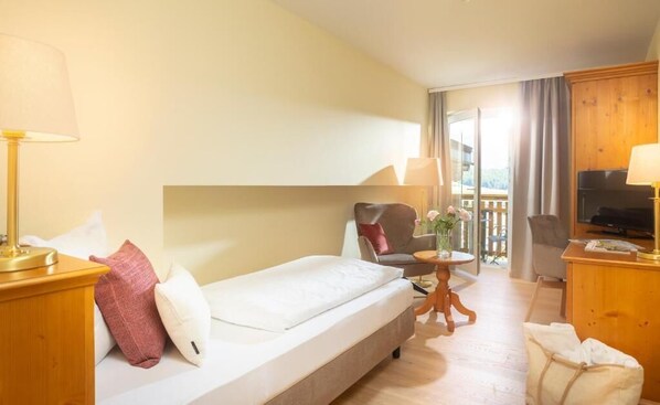 A hotel room with a bed, a desk, a chair, a TV, and a balcony.