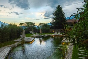 A serene outdoor pool area with lounge chairs and a wooden deck. - Hotel Seppl (Mutters)