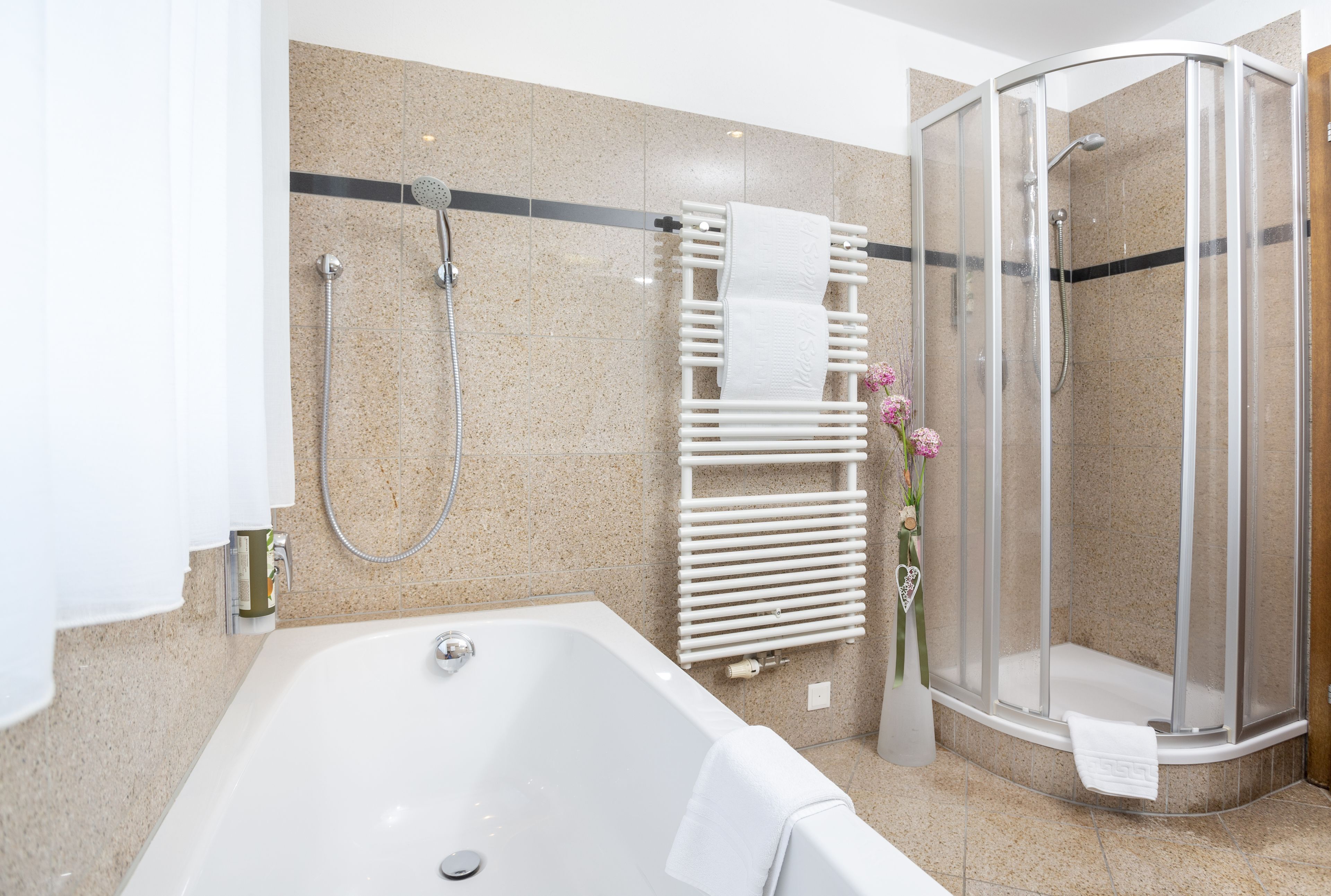 A modern bathroom with a freestanding bathtub, a glass-enclosed shower, and a towel rack with a white towel.