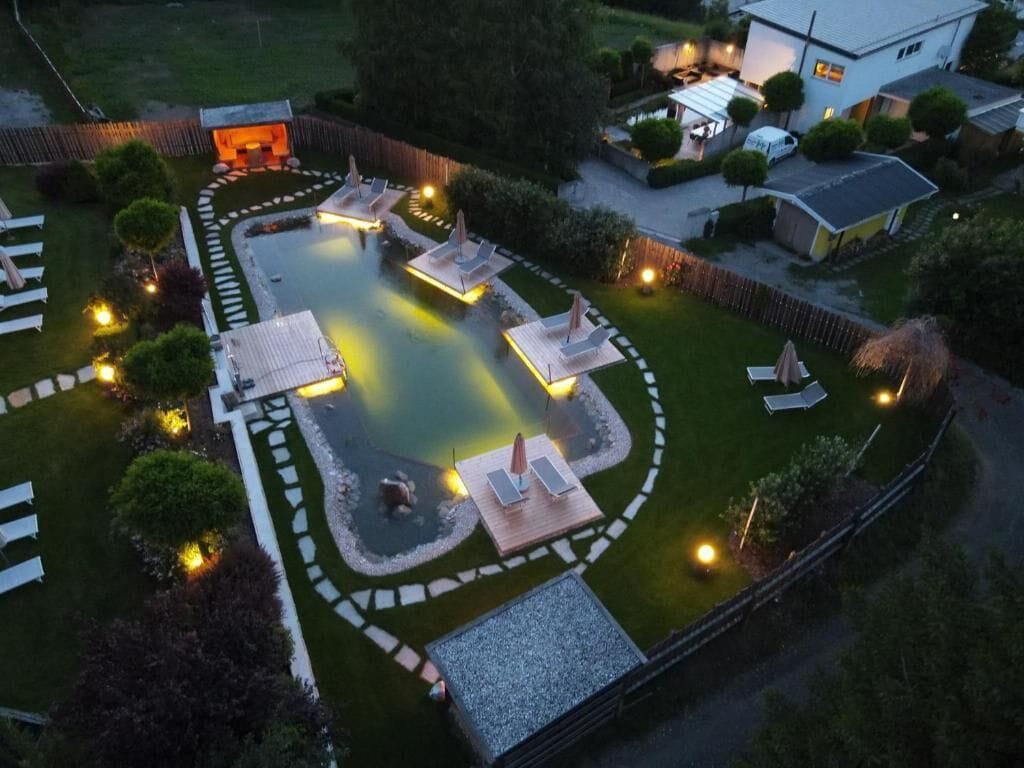 Ein gepflegter Außenbereich mit Schwimmbad, Liegestühlen und einer kleinen Holzterrasse.