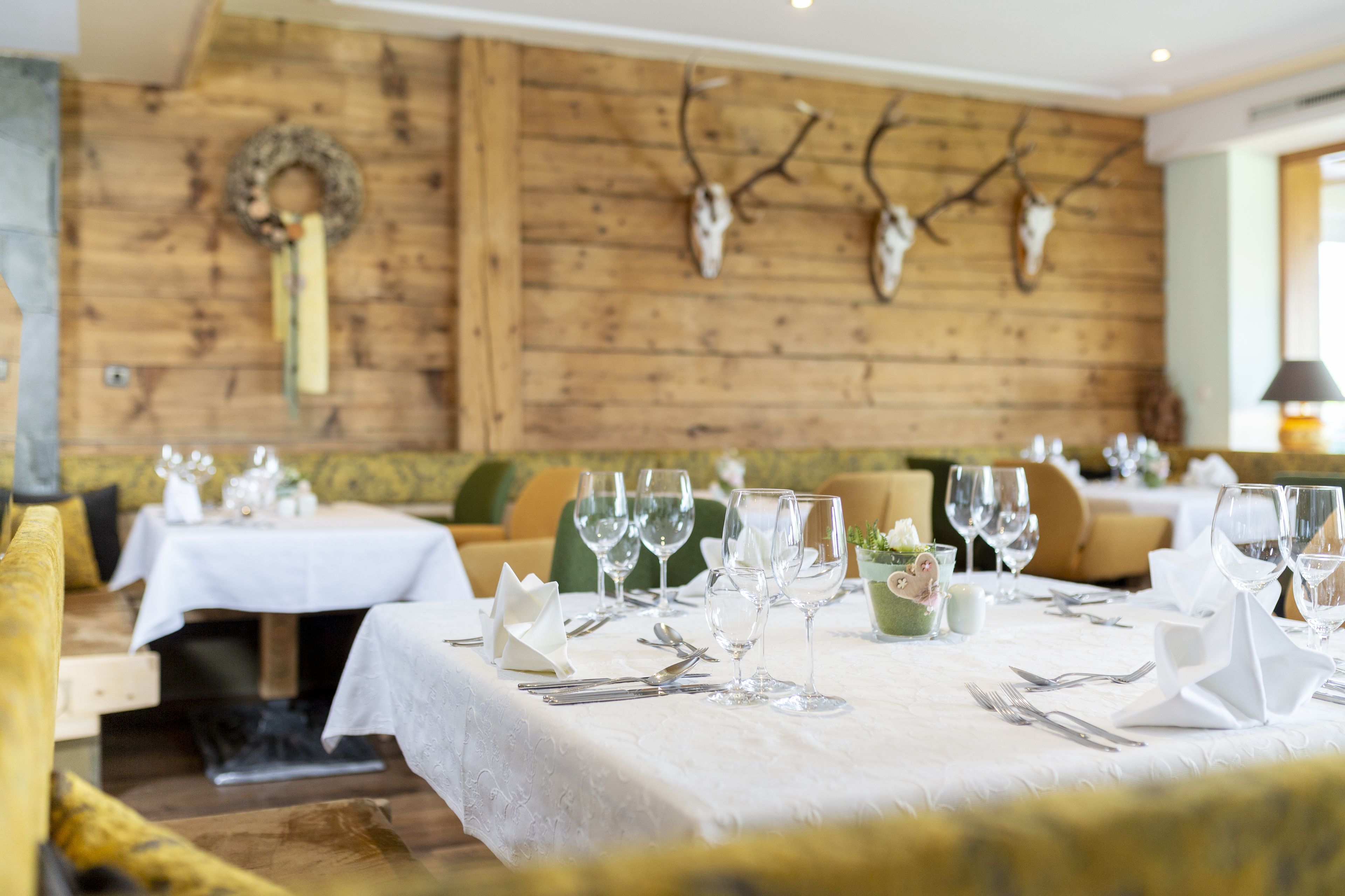 Un restaurante con paredes de madera, decoraciones de asta de ciervo y mesas dispuestas para comer.